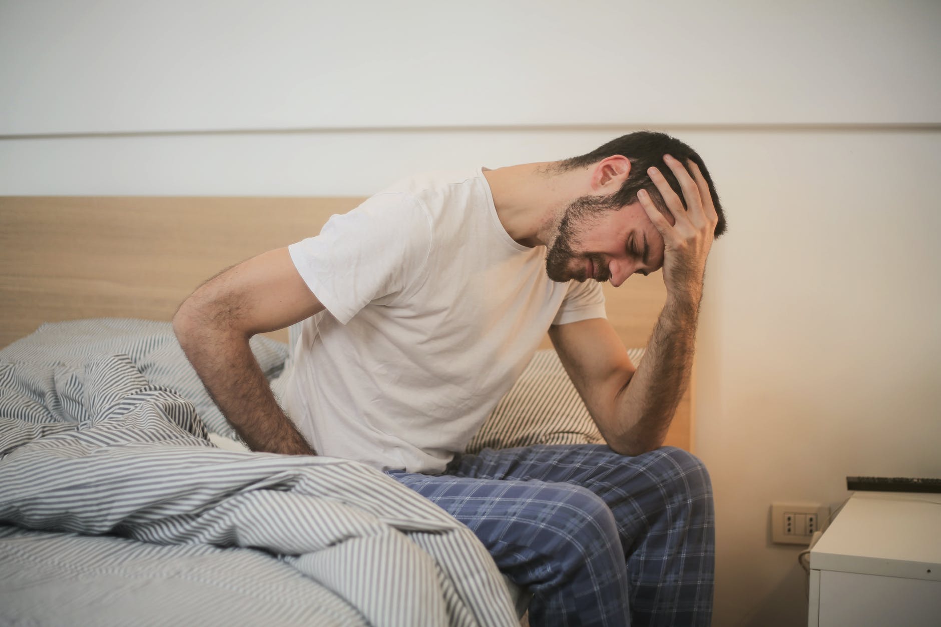 Tired man on edge of bed.