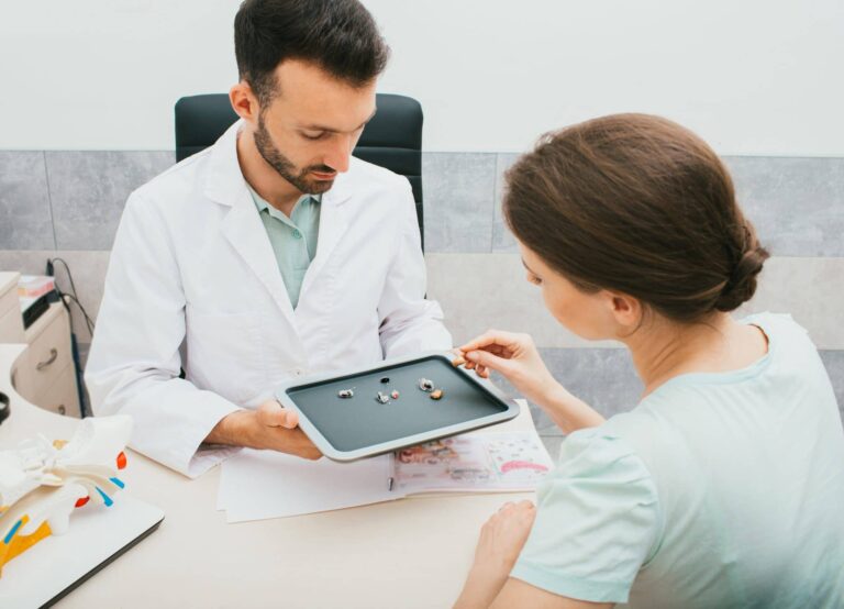 Audiologist selecting a hearing aid for a female patient.