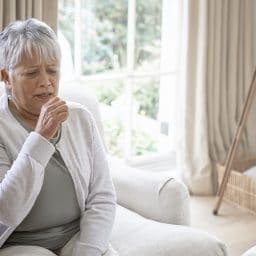 Woman coughing in her living room at home.