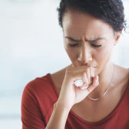 Woman coughing at her desk.