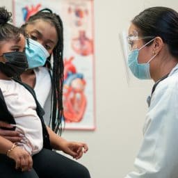 Mother and daughter talk to a pediatric doctor.