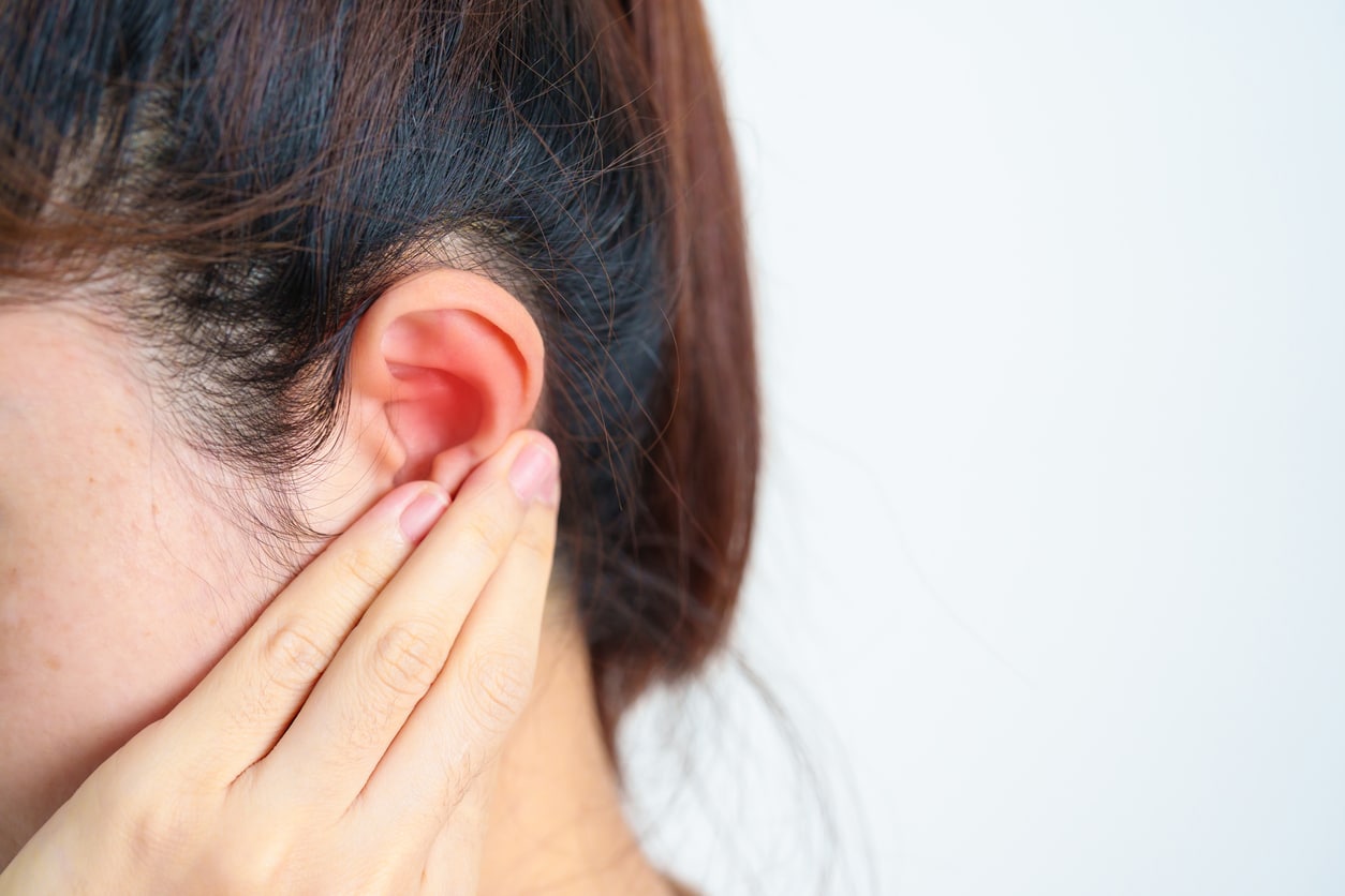 Woman holds hand behind ear
