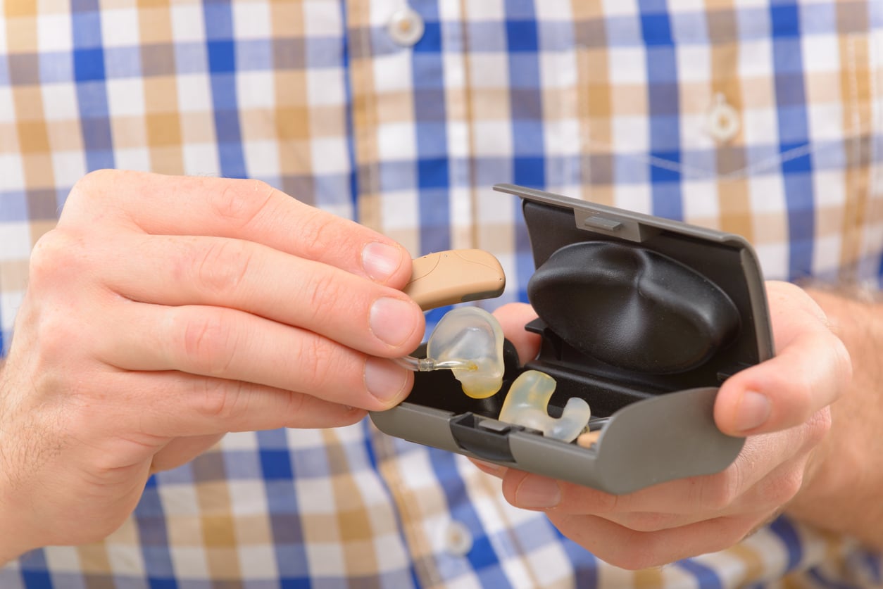 Close up of a person holding new hearing aids in a hearing aid case.