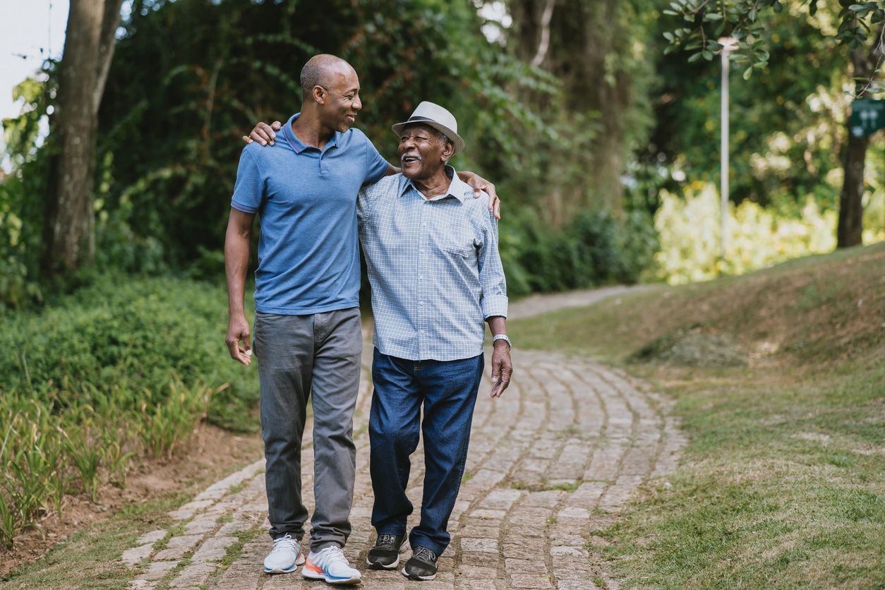 Happy father and son walking together through a park.