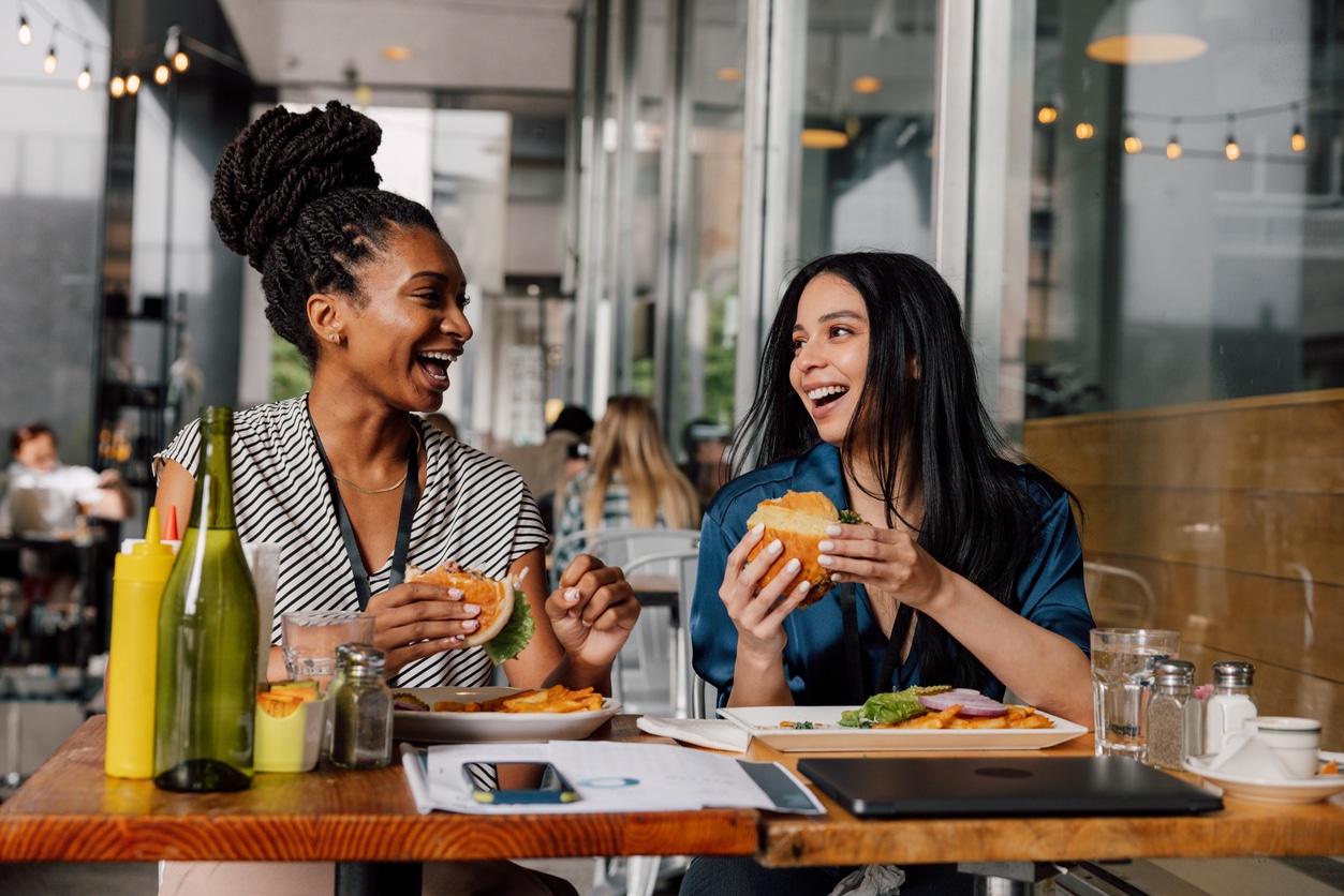 Two happy women eating lunch together at a cafe